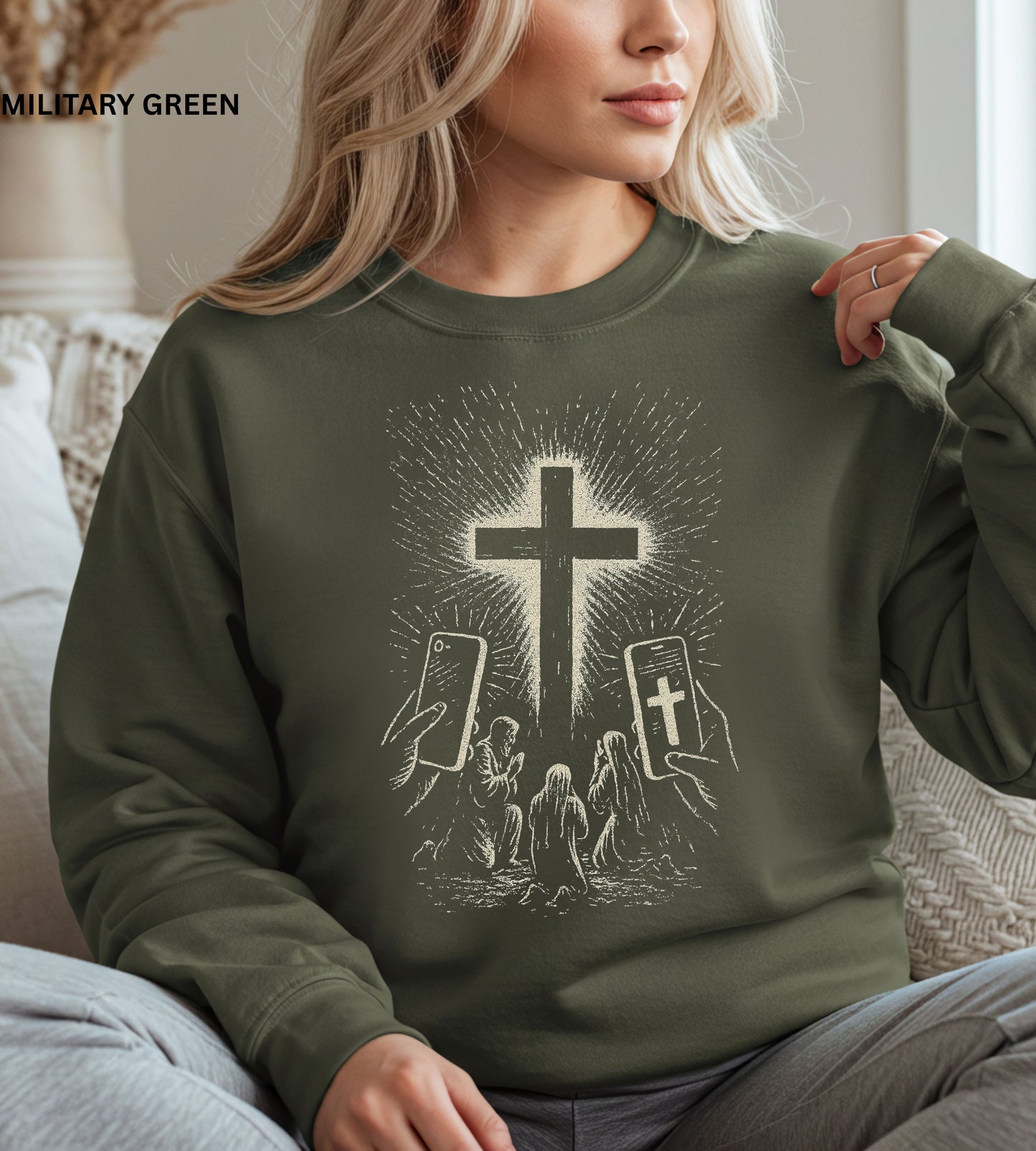 Person wearing a military green sweatshirt with a graphic design of hands holding smartphones with crosses on the screens.

