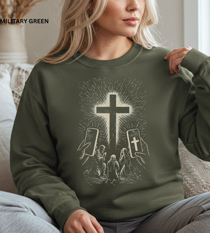 Person wearing a military green sweatshirt with a graphic design of hands holding smartphones with crosses on the screens.

