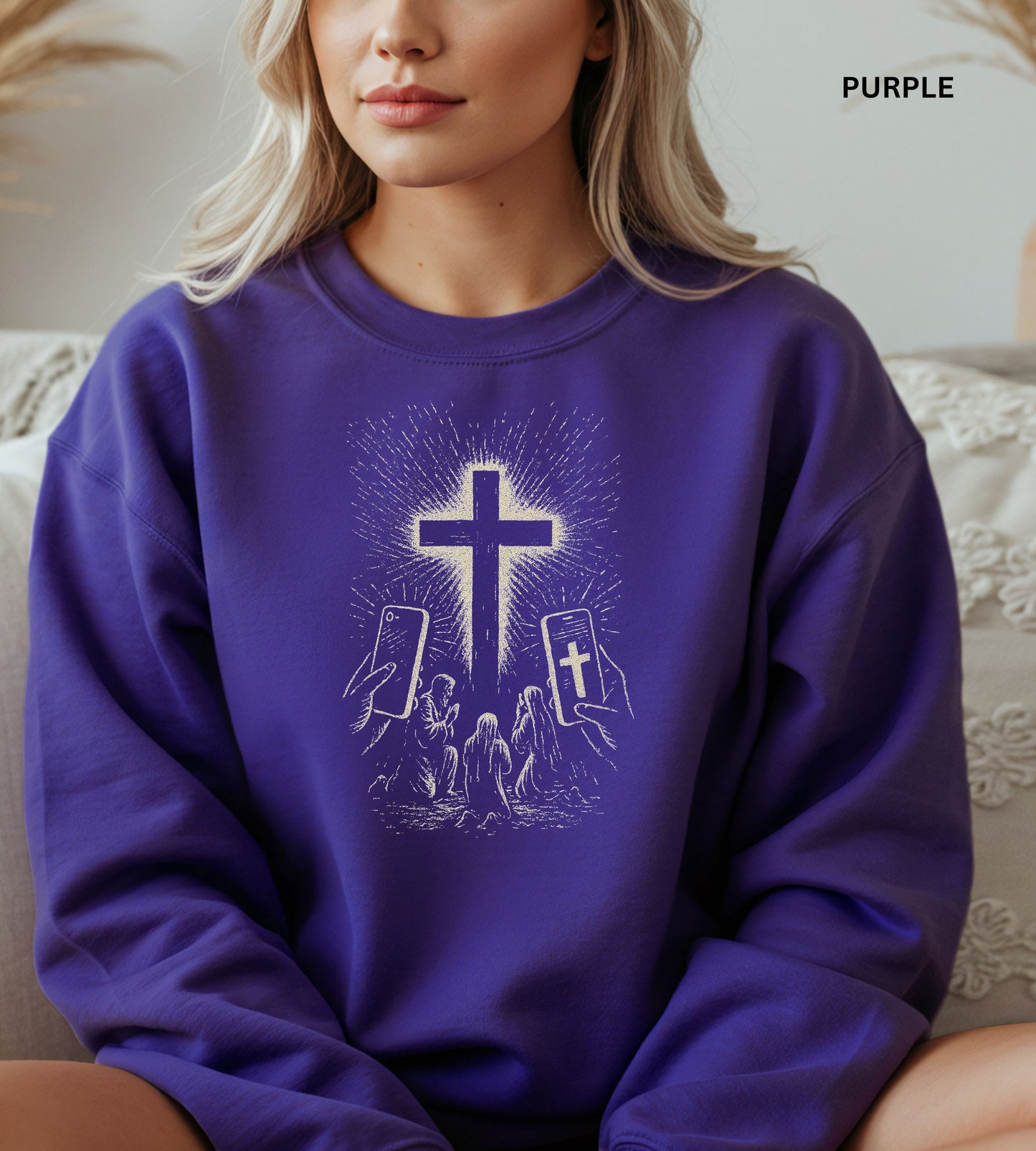 Person wearing a purple sweatshirt with a graphic design of hands holding smartphones with crosses on the screens.

