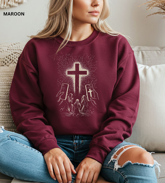 Person wearing a maroon sweatshirt with a cross design, sitting on a couch.