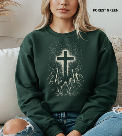 Person wearing a forest green sweatshirt with a graphic design of hands holding smartphones with crosses on the screens.

