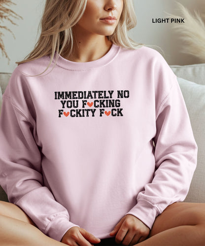 Light pink sweatshirt with graphic text worn by a person sitting on a couch.