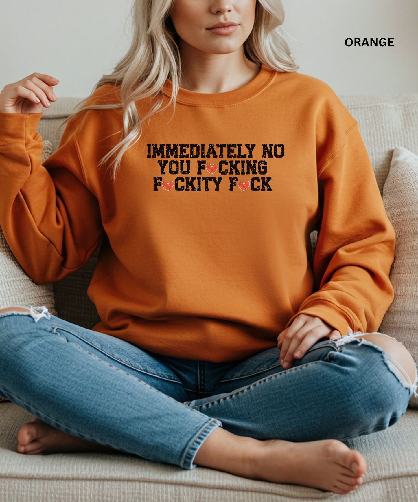 Person wearing an orange sweatshirt with a graphic design sitting on a couch.