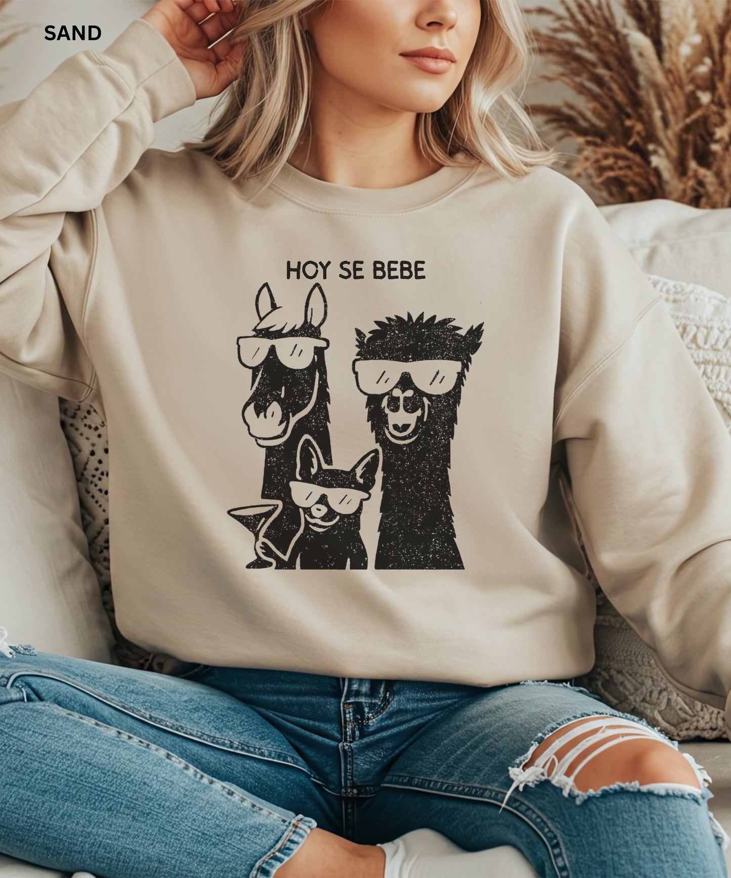 Person wearing a sand sweatshirt with llama and dog graphic and 'HOY SE BEBE' text.