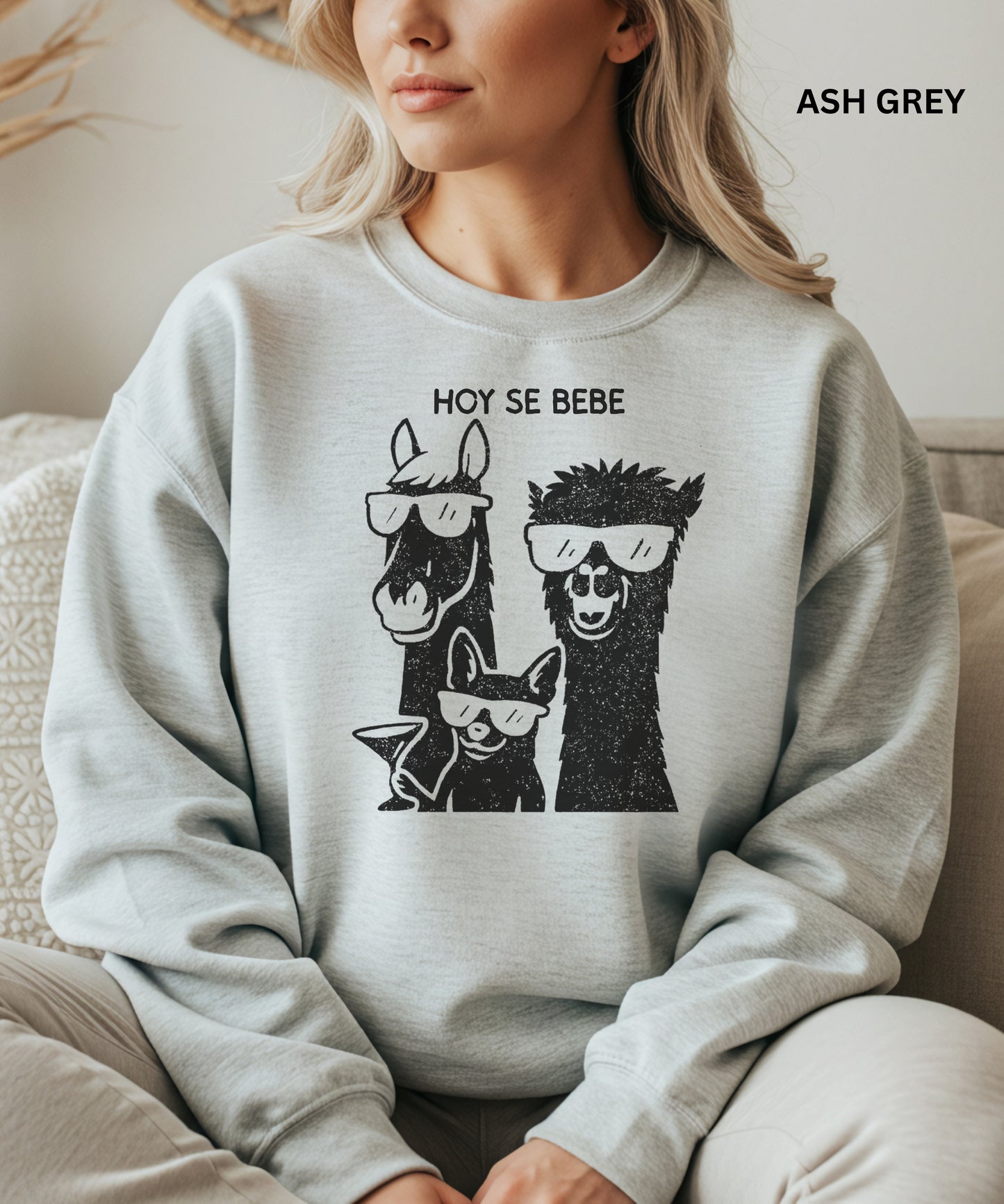 Person wearing an ash grey sweatshirt with llama and dog graphic and 'HOY SE BEBE' text.
