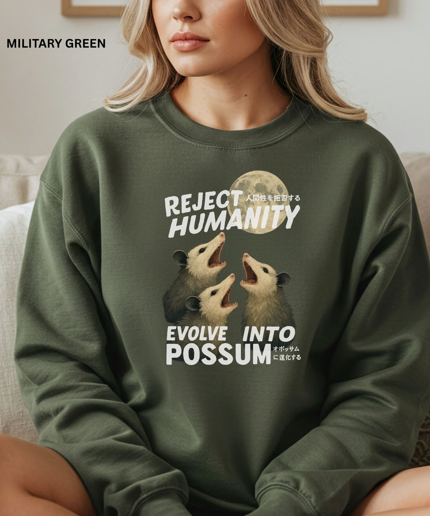 Person wearing a military green colored sweatshirt with a graphic design that says "reject humanity evolve into possum" sitting on a couch.