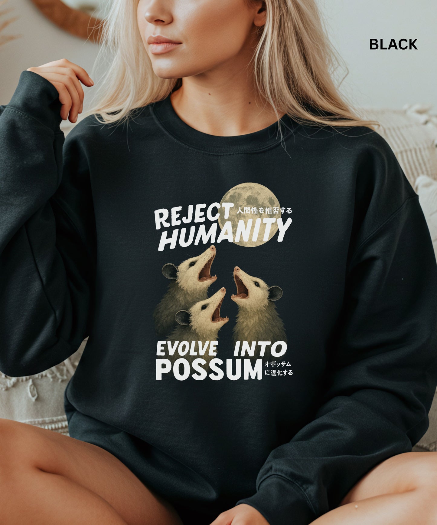 Person wearing a black colored sweatshirt with a graphic design that says "reject humanity evolve into possum" sitting on a couch.