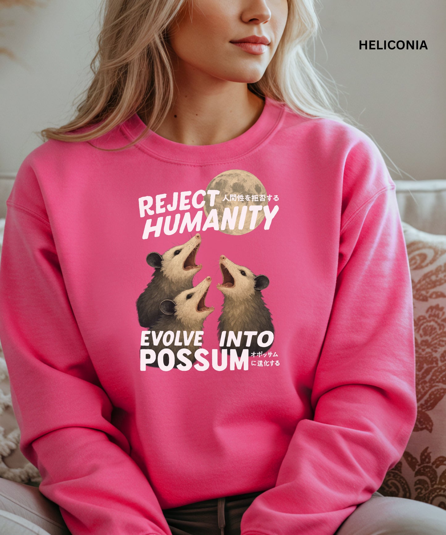 Person wearing a heliconia colored sweatshirt with a graphic design that says "reject humanity evolve into possum" sitting on a couch.