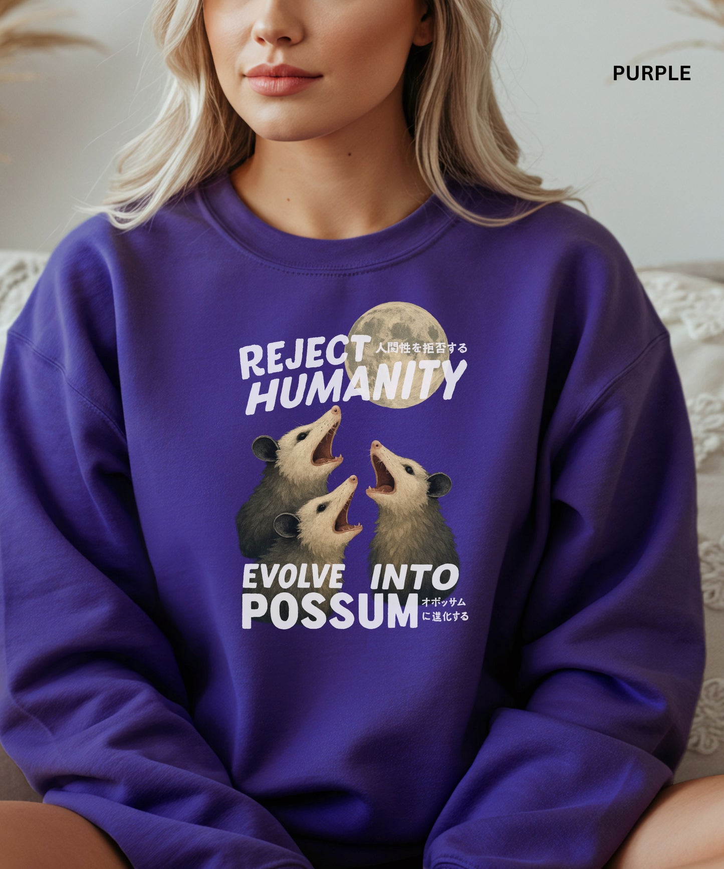Person wearing a purple colored sweatshirt with a graphic design that says "reject humanity evolve into possum" sitting on a couch.