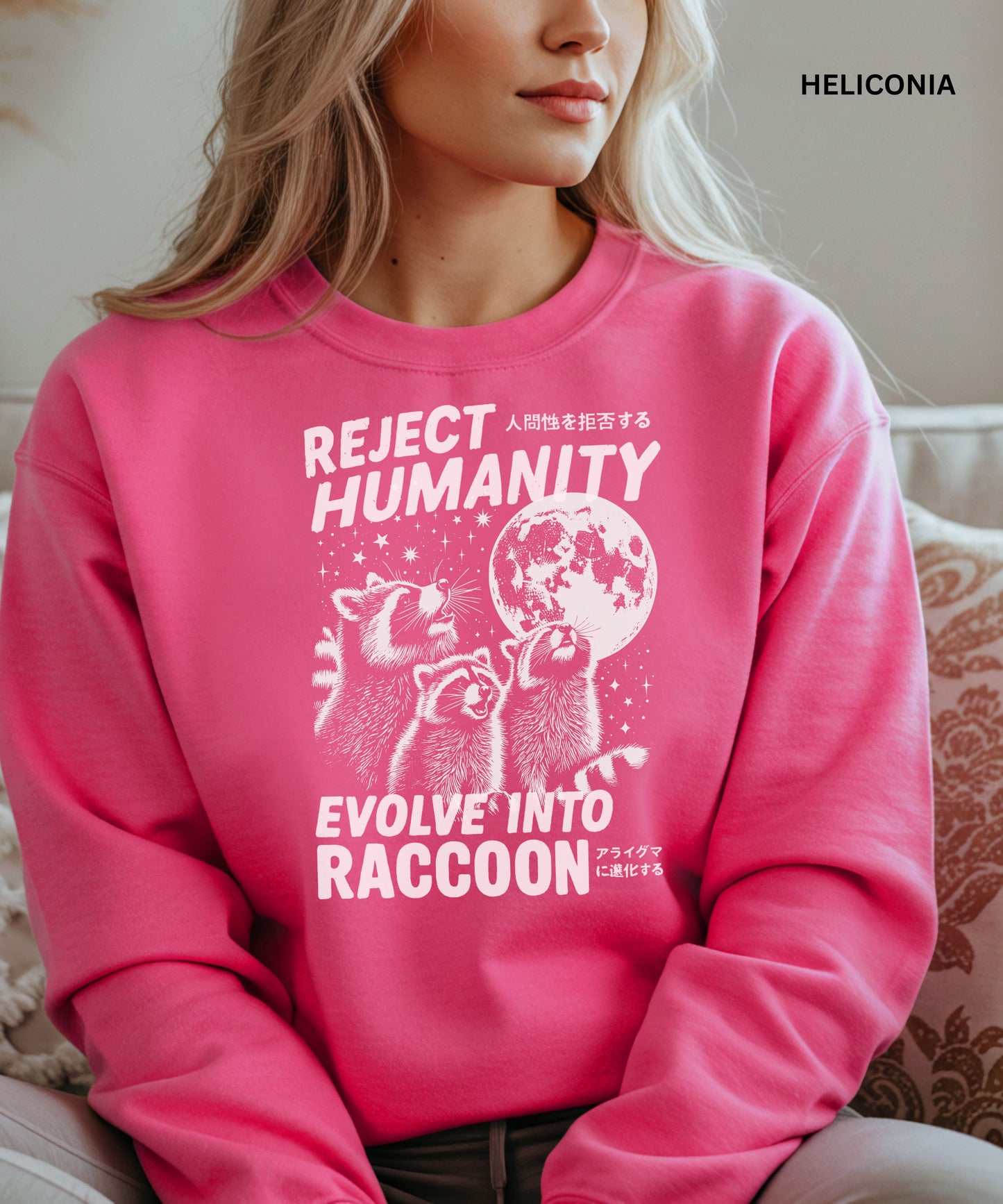 Person wearing a Heliconia colored sweatshirt with a graphic design that says "reject humanity evolve into racoon" sitting on a couch.