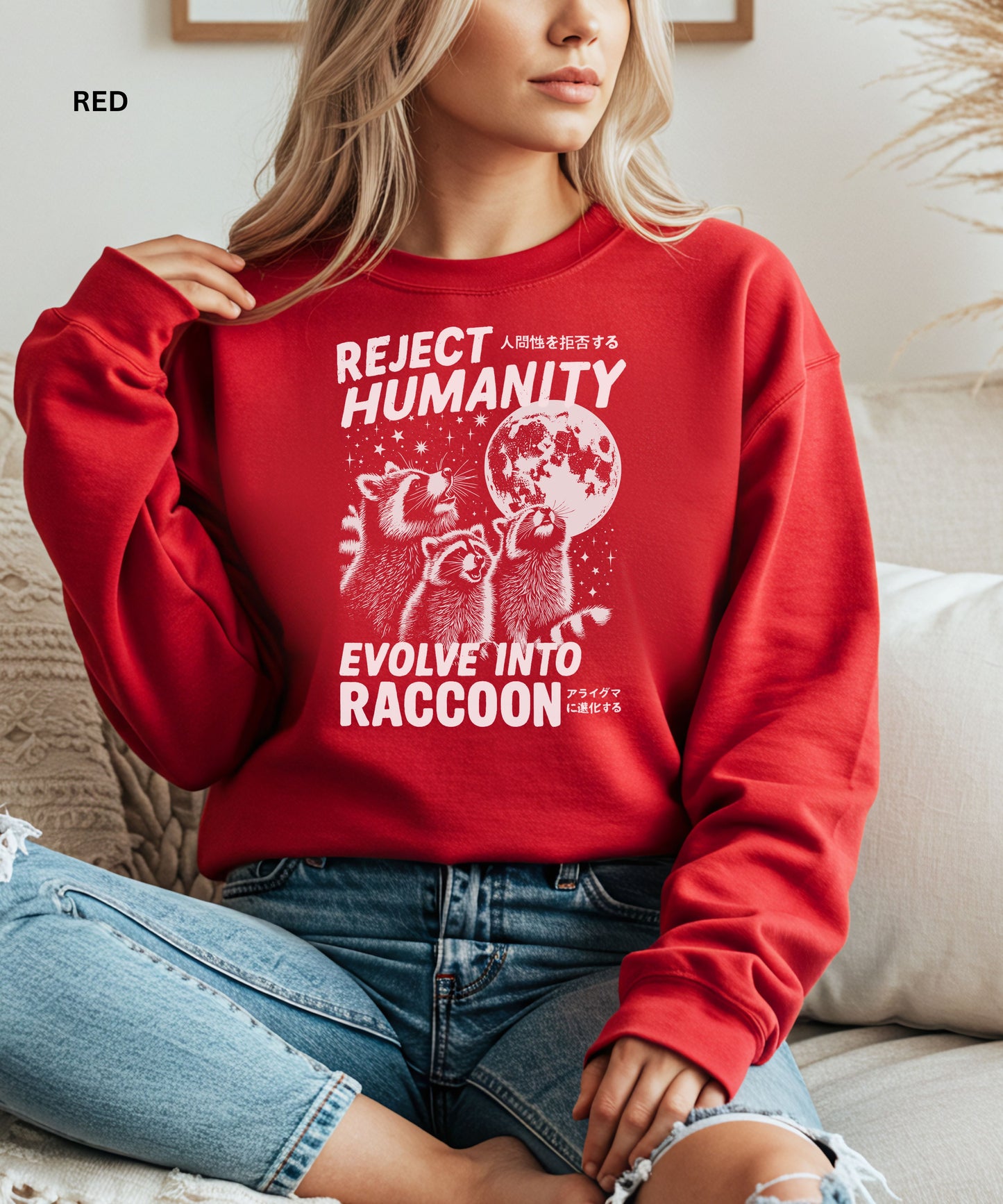 Person wearing a red colored sweatshirt with a graphic design that says "reject humanity evolve into racoon" sitting on a couch.