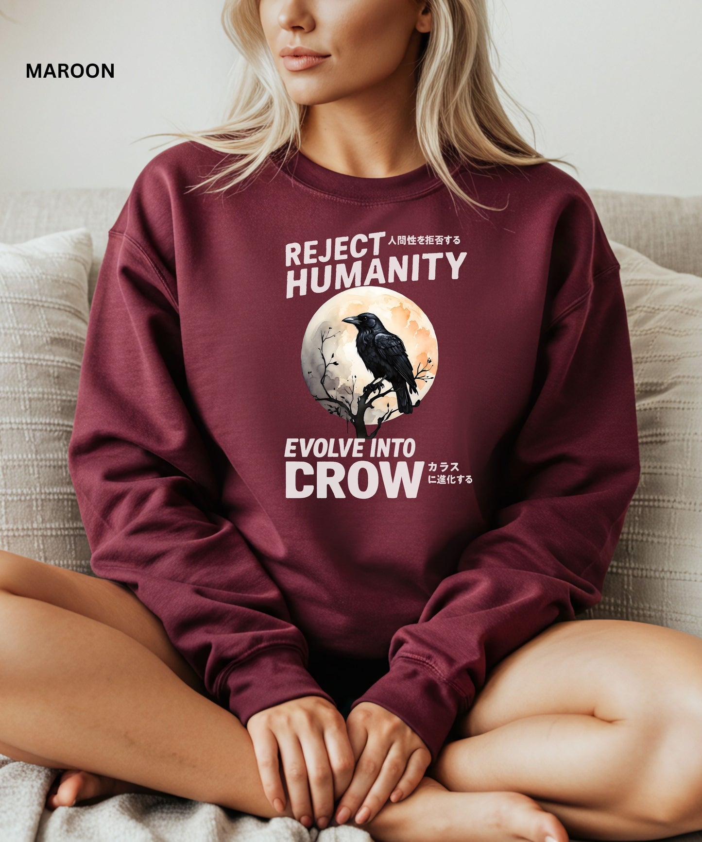 Person wearing a maroon sweatshirt with a graphic design that says "reject humanity evolve into crow" sitting on a couch.