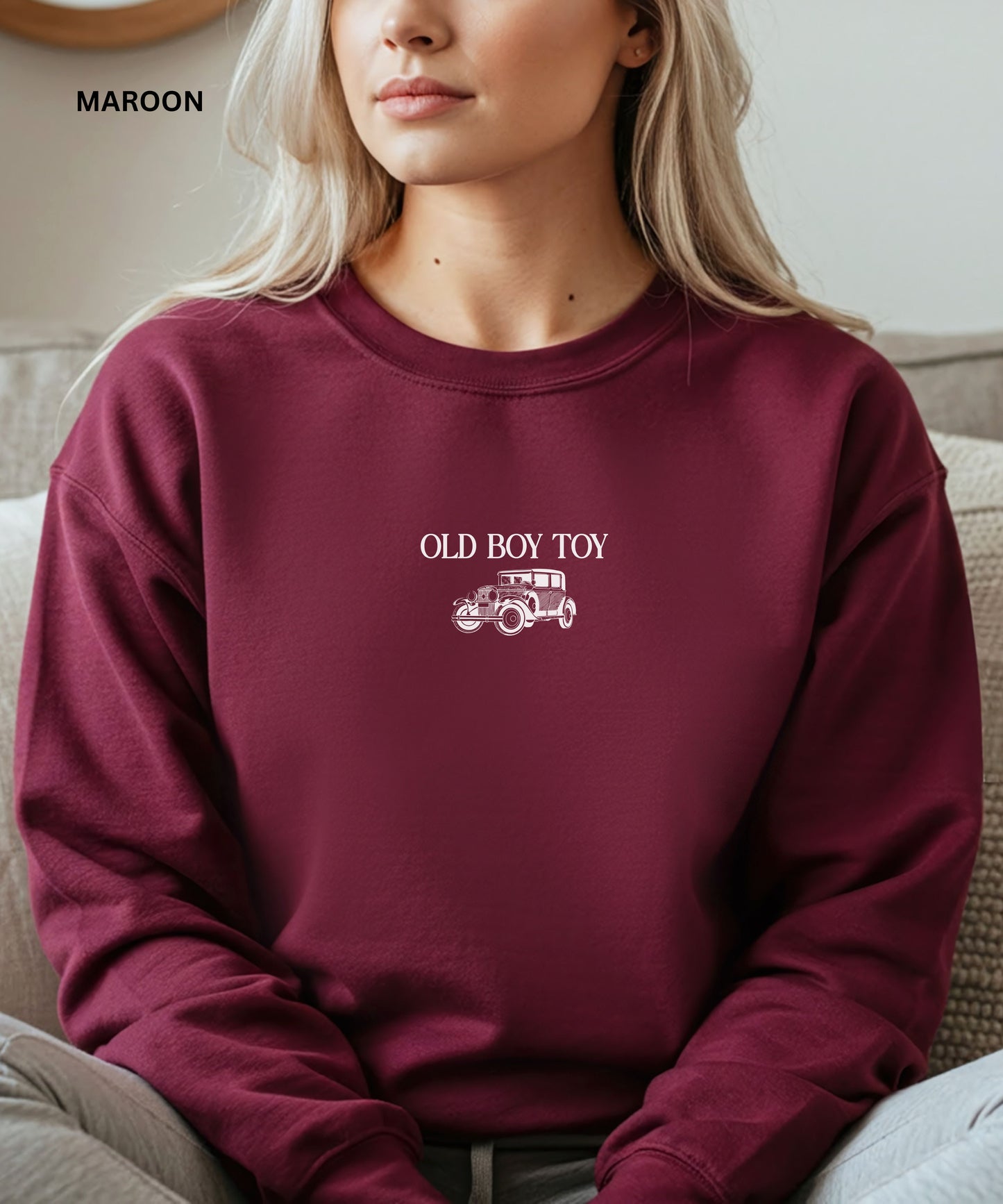 Maroon sweatshirt with 'Old Boy Toy' text and car graphic worn by a person.