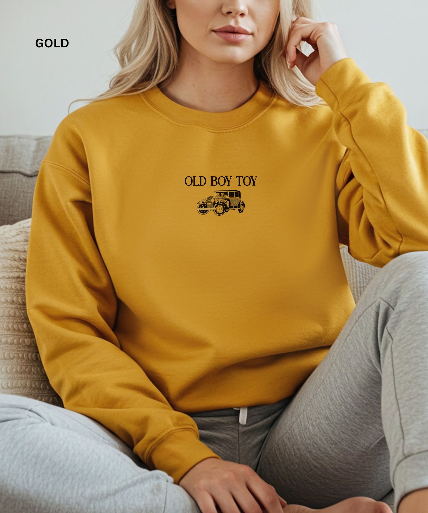 Person wearing a yellow sweatshirt with 'Old Boy Toy' text and vintage car graphic.