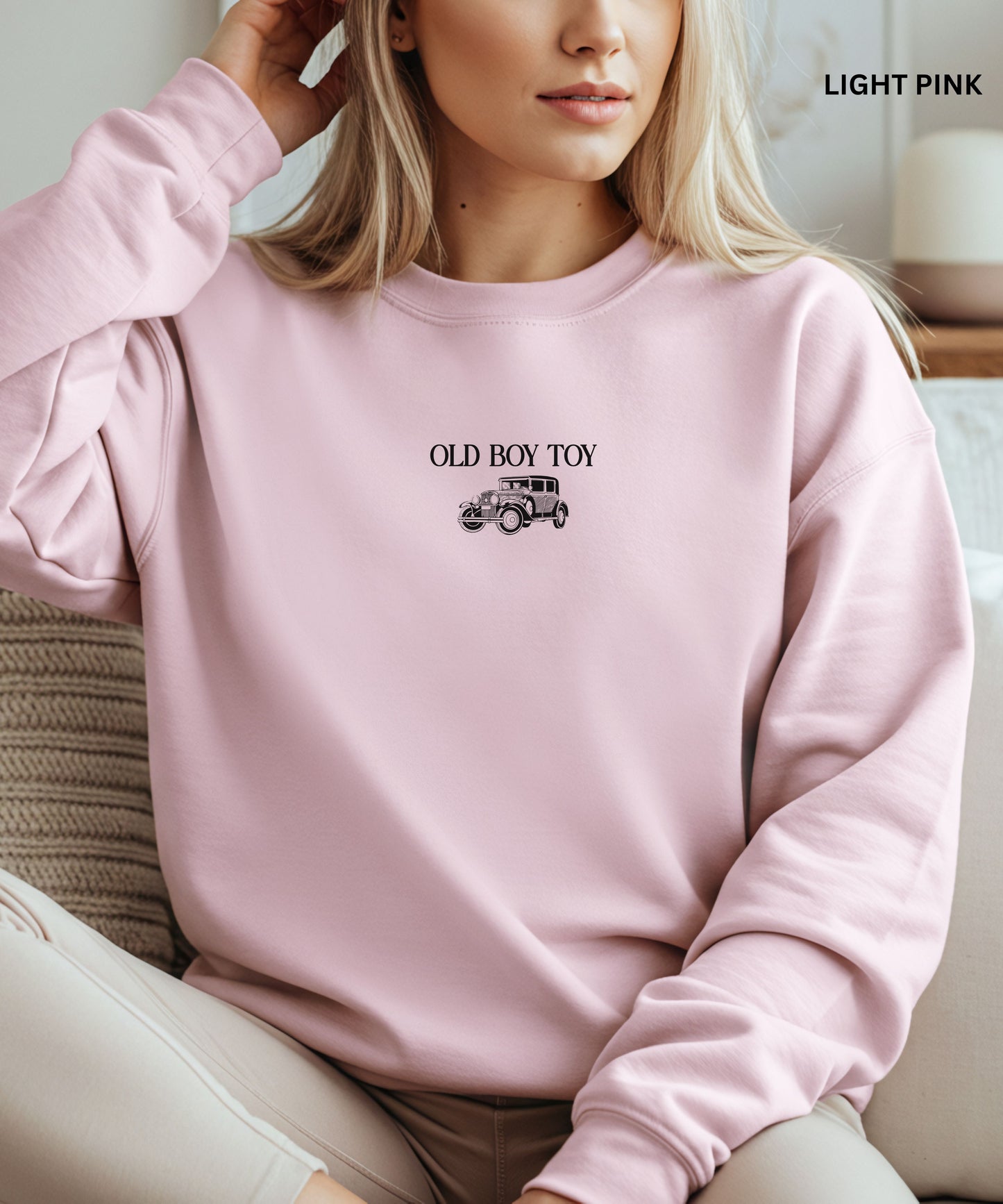 Person wearing a light pink sweatshirt with 'Old Boy Toy' text and car graphic.