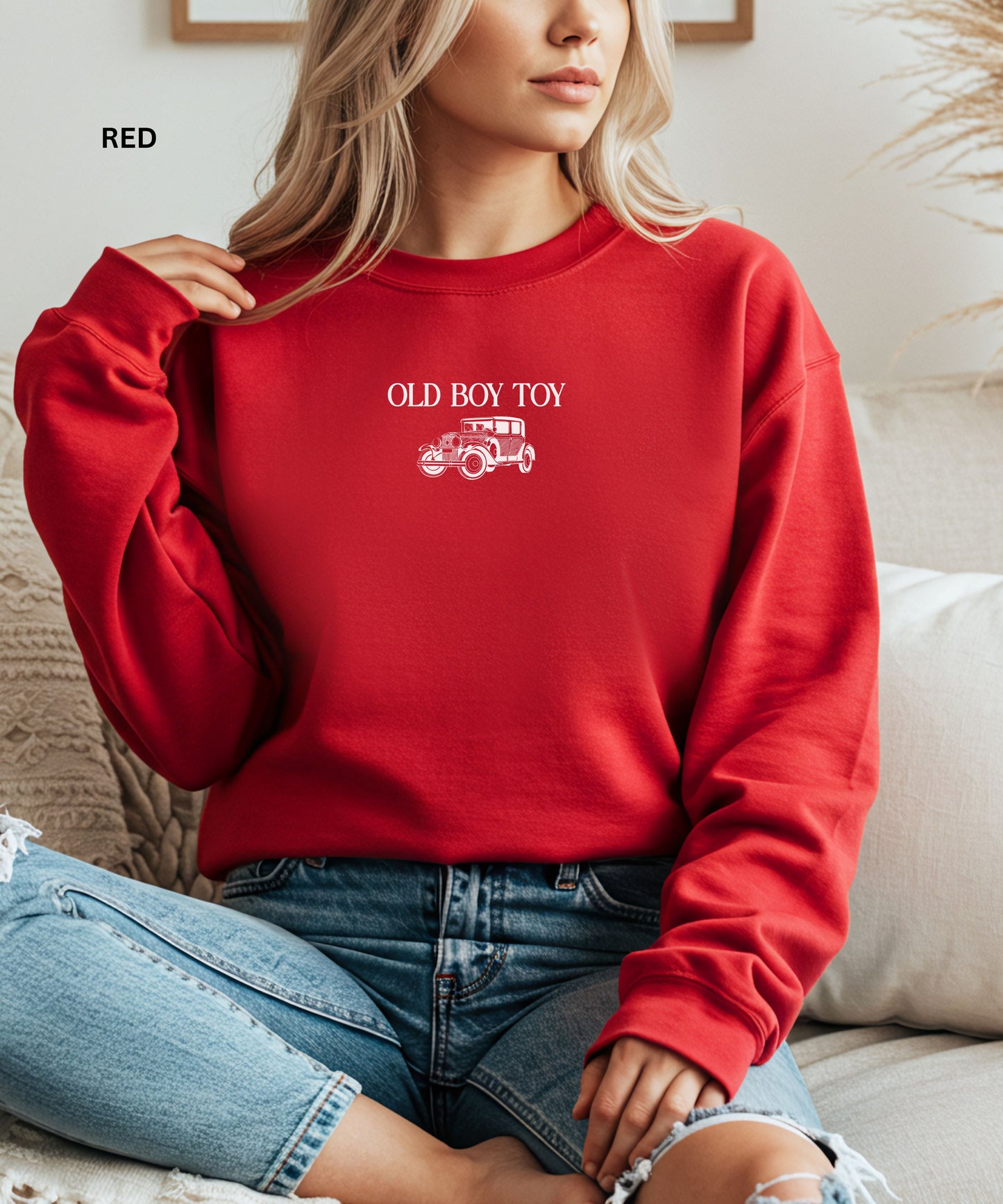 Person wearing a red sweatshirt with 'Old Boy Toy' text and graphic, sitting on a couch.