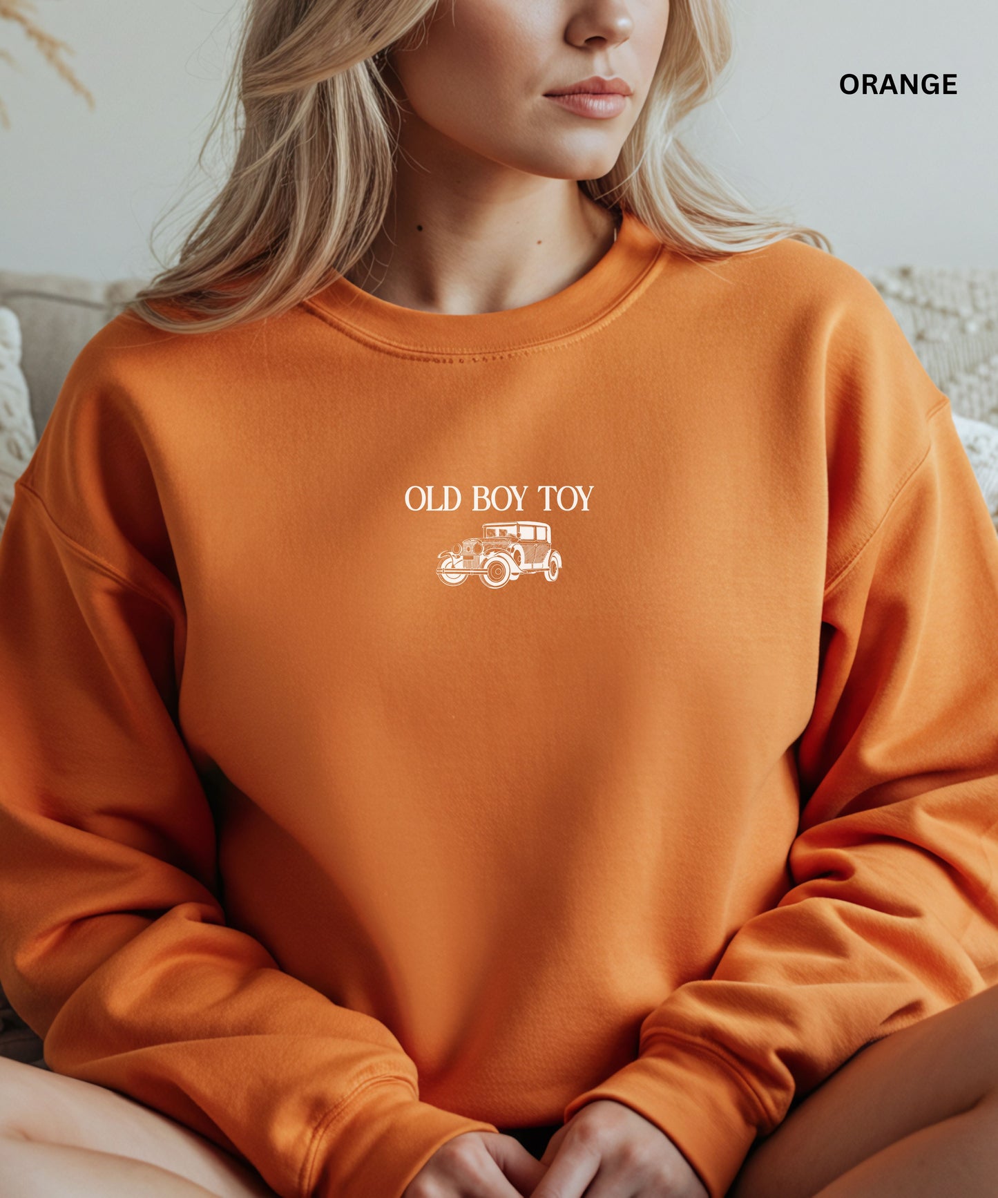 Person wearing an orange sweatshirt with 'OLD BOY TOY' text and graphic.