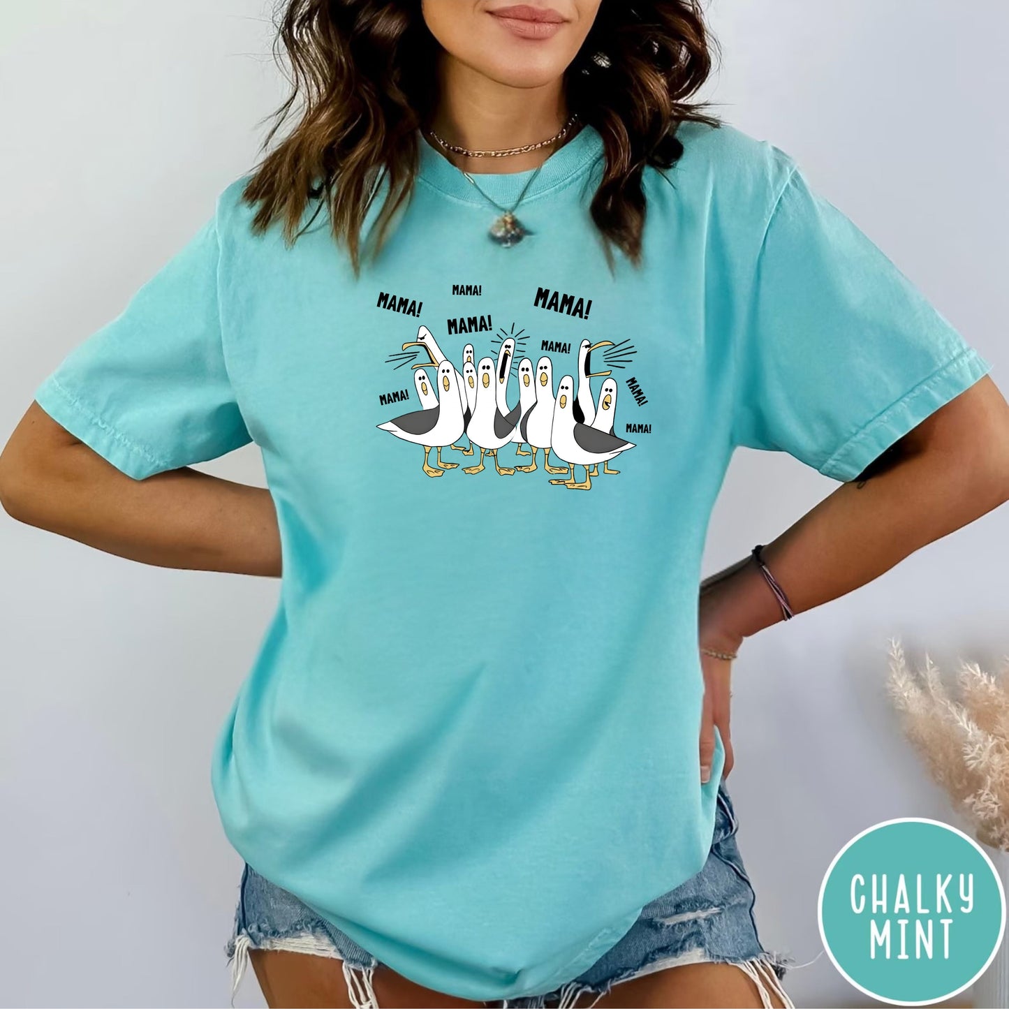 chalky mint  t-shirt with cartoon penguins screaming "Mama"  design and text worn by a person.