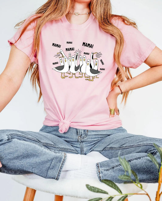 light pink t-shirt with cartoon penguins screaming "Mama"  design and text worn by a person.