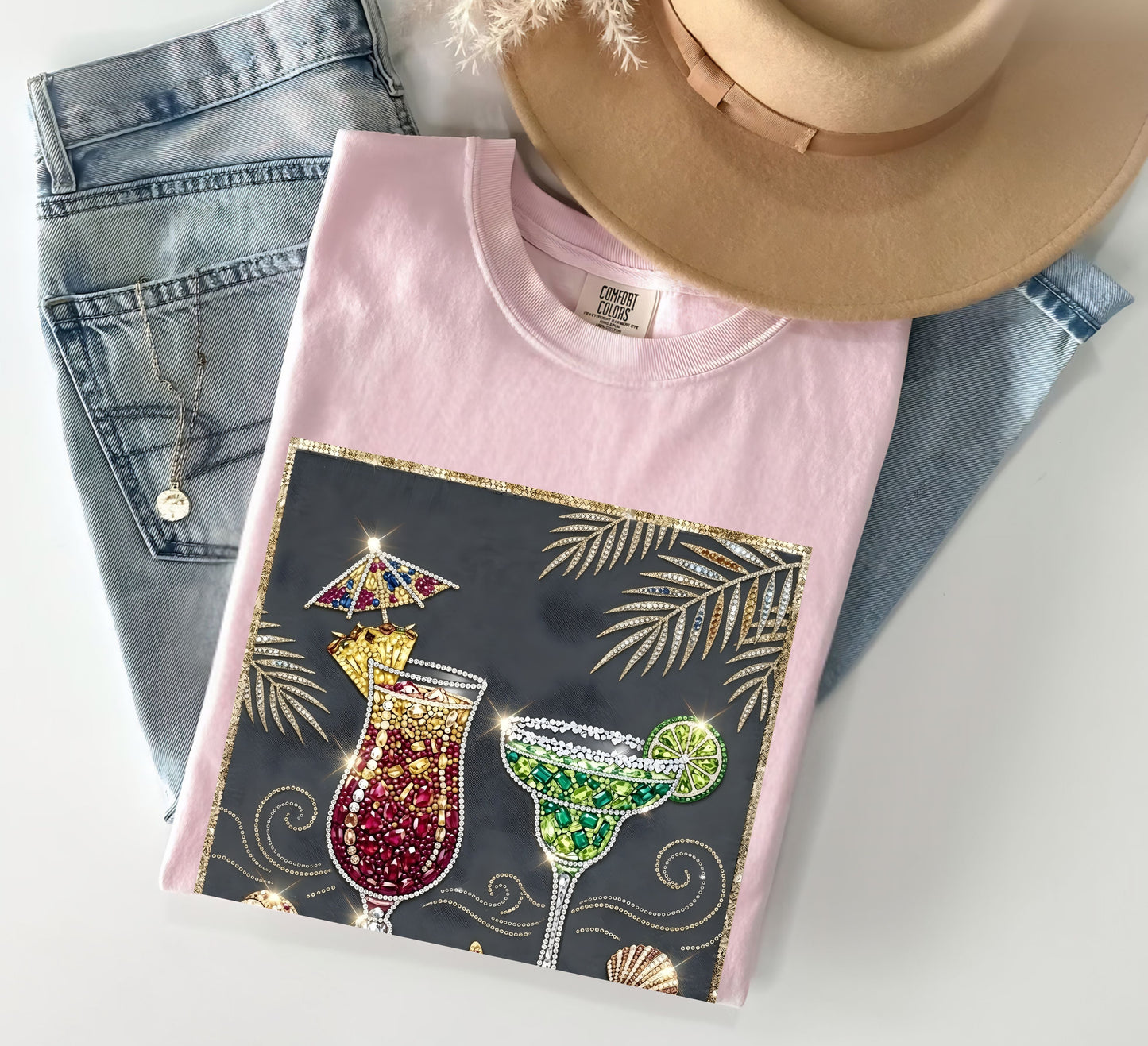 blossom t-shirt with cocktail design on a white surface with jeans and a hat.