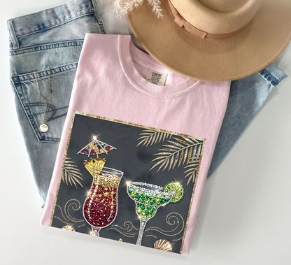 blossom t-shirt with cocktail design on a white surface with jeans and a hat.
