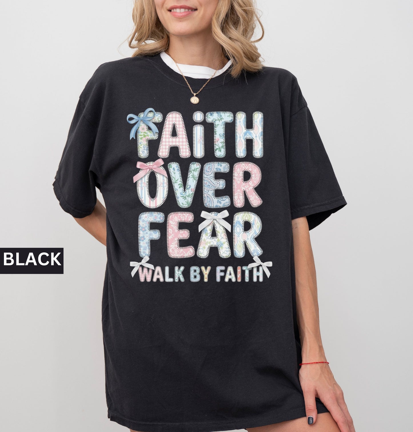 Black t-shirt with 'Faith Over Fear' text worn by a person on a plain background