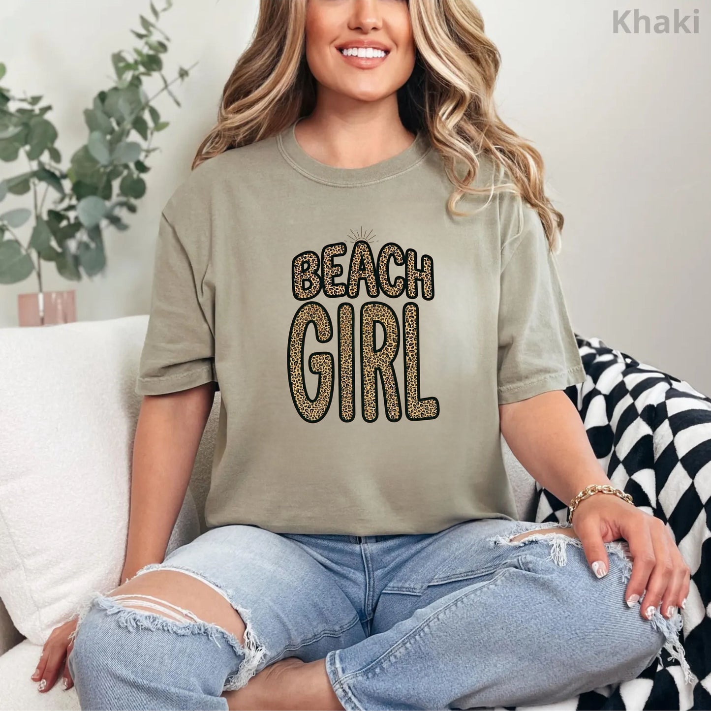 Person wearing a khaki t-shirt with 'Beach Girl' text, sitting on a couch.