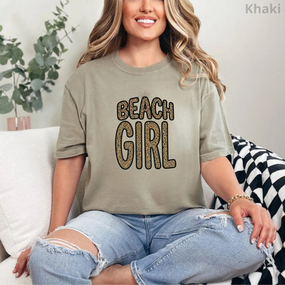 Person wearing a khaki t-shirt with 'Beach Girl' text, sitting on a couch.