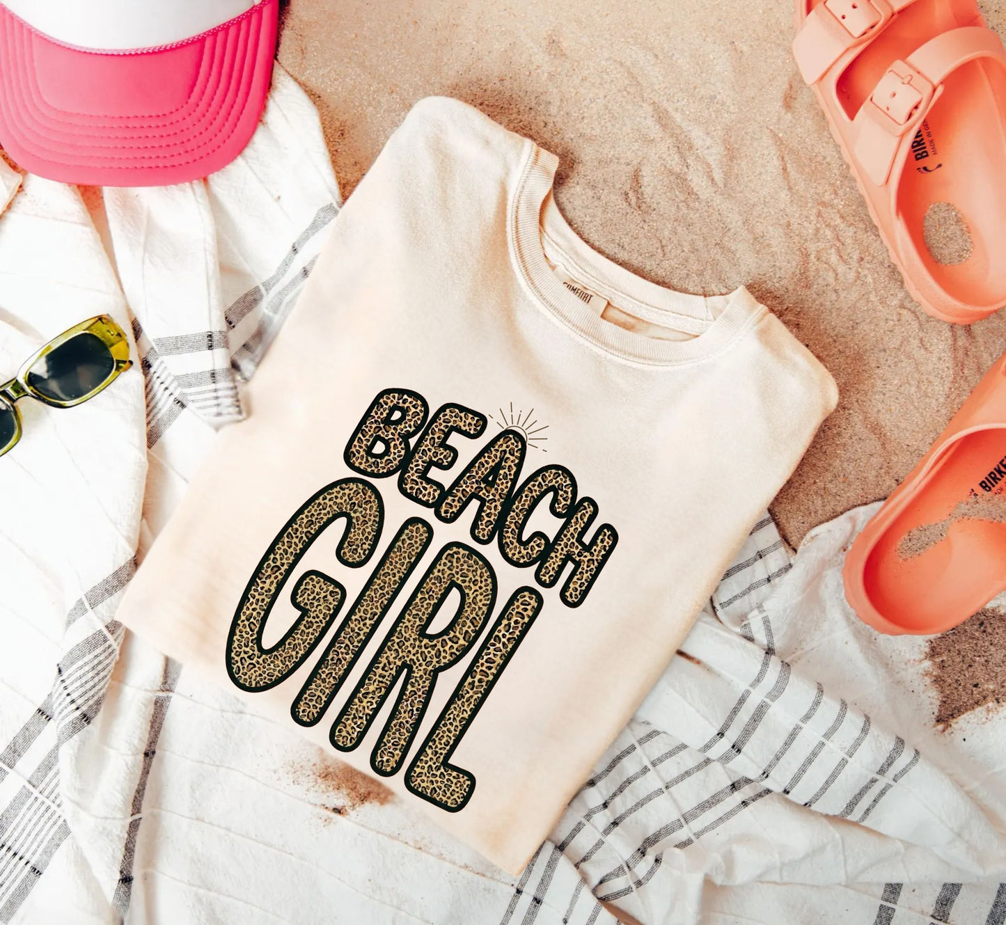 Ivory color Beach-themed t-shirt with 'Beach Girl' text on sand with accessories.
