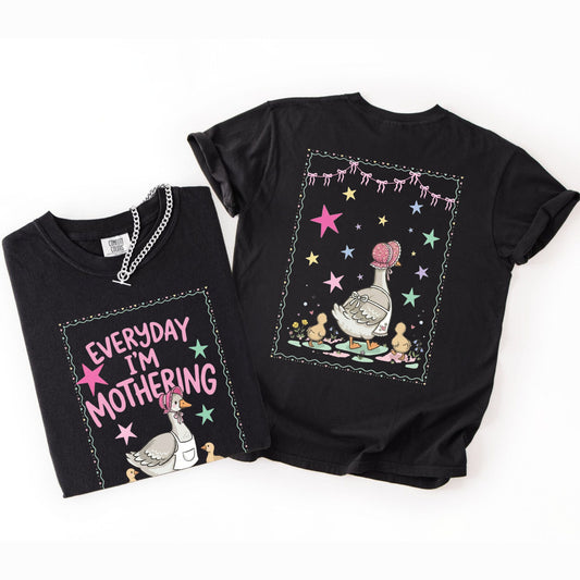 Two black t-shirts with front and back graphic designs of a mother goose her ducklings with phrase "everyday im mothering" and text on a white background