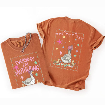 Two yam colored  t-shirts with front and back graphic designs of a mother goose her ducklings with phrase "everyday im mothering" and text on a white background