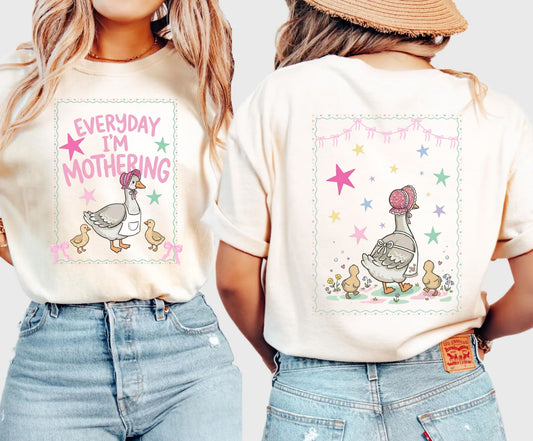 Two ivory t-shirts with front and back graphic designs of a mother goose her ducklings with phrase "everyday im mothering" and text on a white background