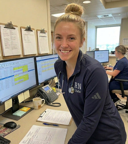 Nurse in a navy blue shirt with 'RN' on a desk in a medical office setting.