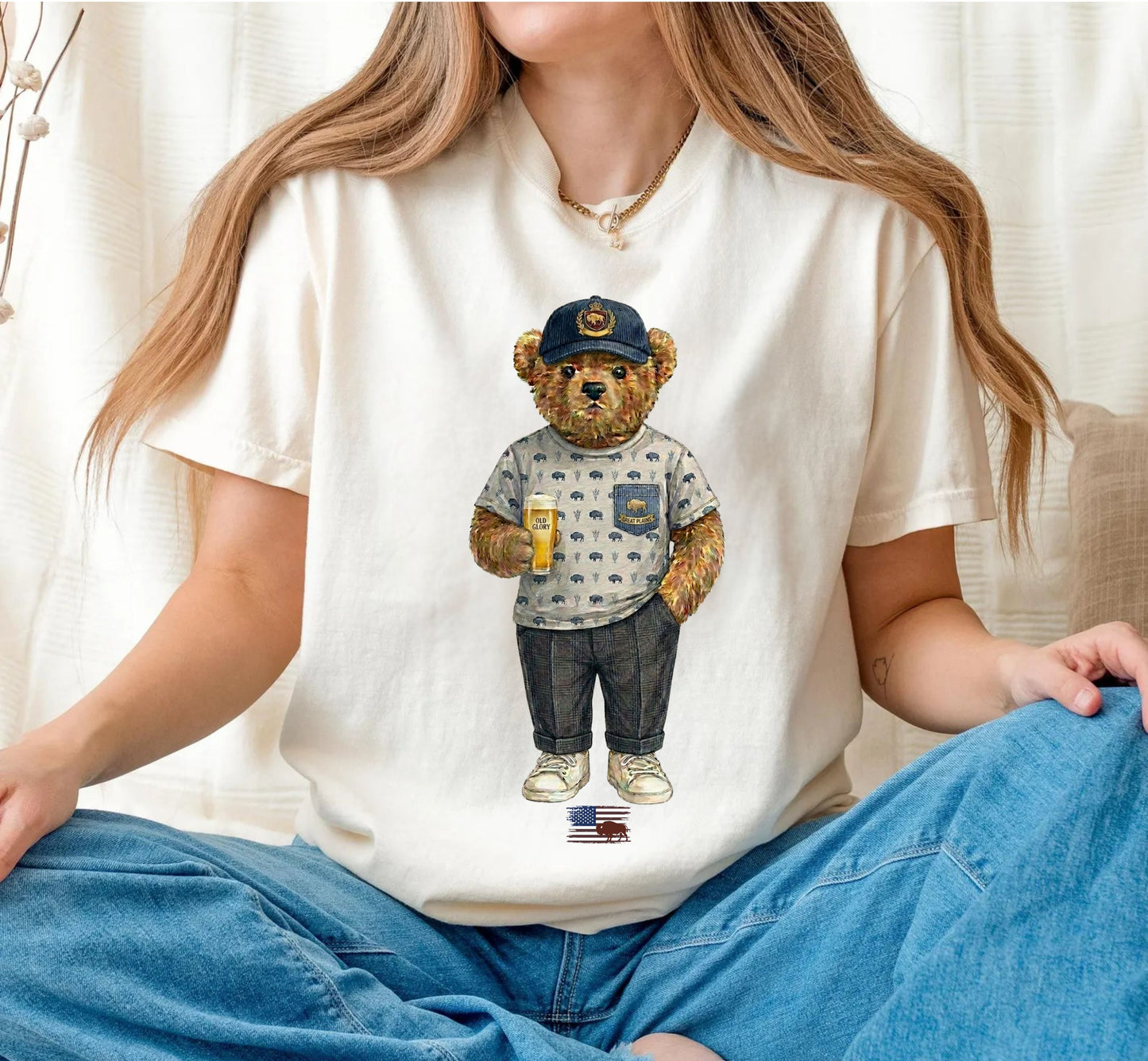 Person wearing an ivory t-shirt with a teddy bear graphic, sitting on a white background