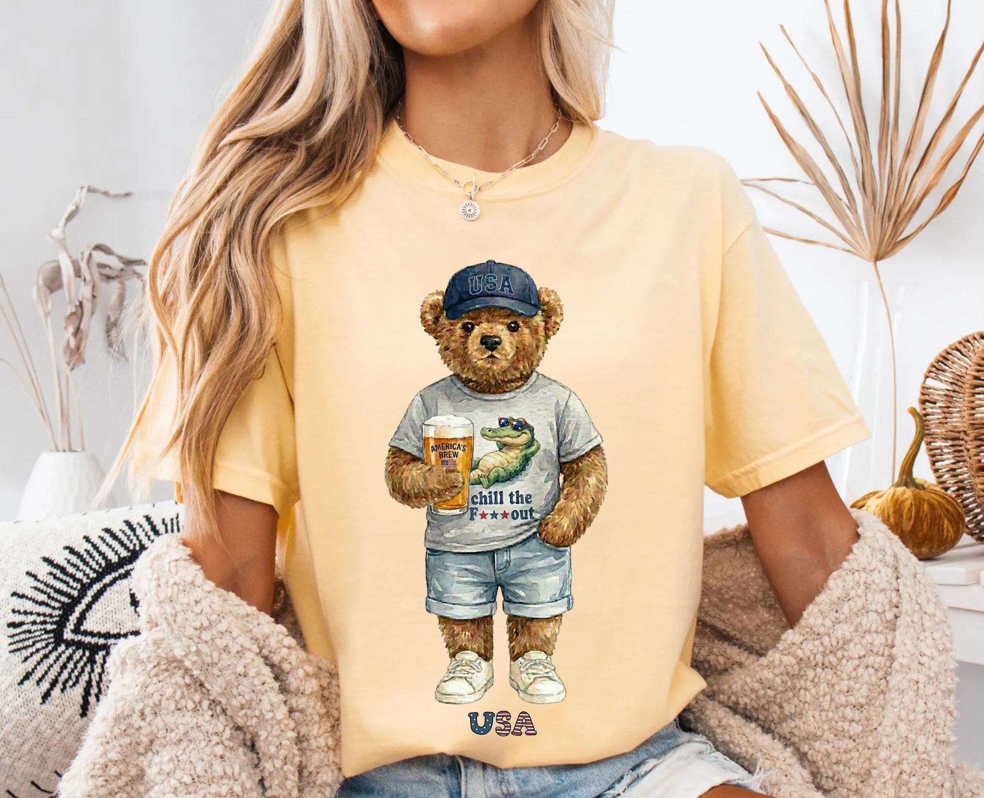 Person wearing a banana t-shirt with a bear graphic holding a beer, sitting in a cozy room.