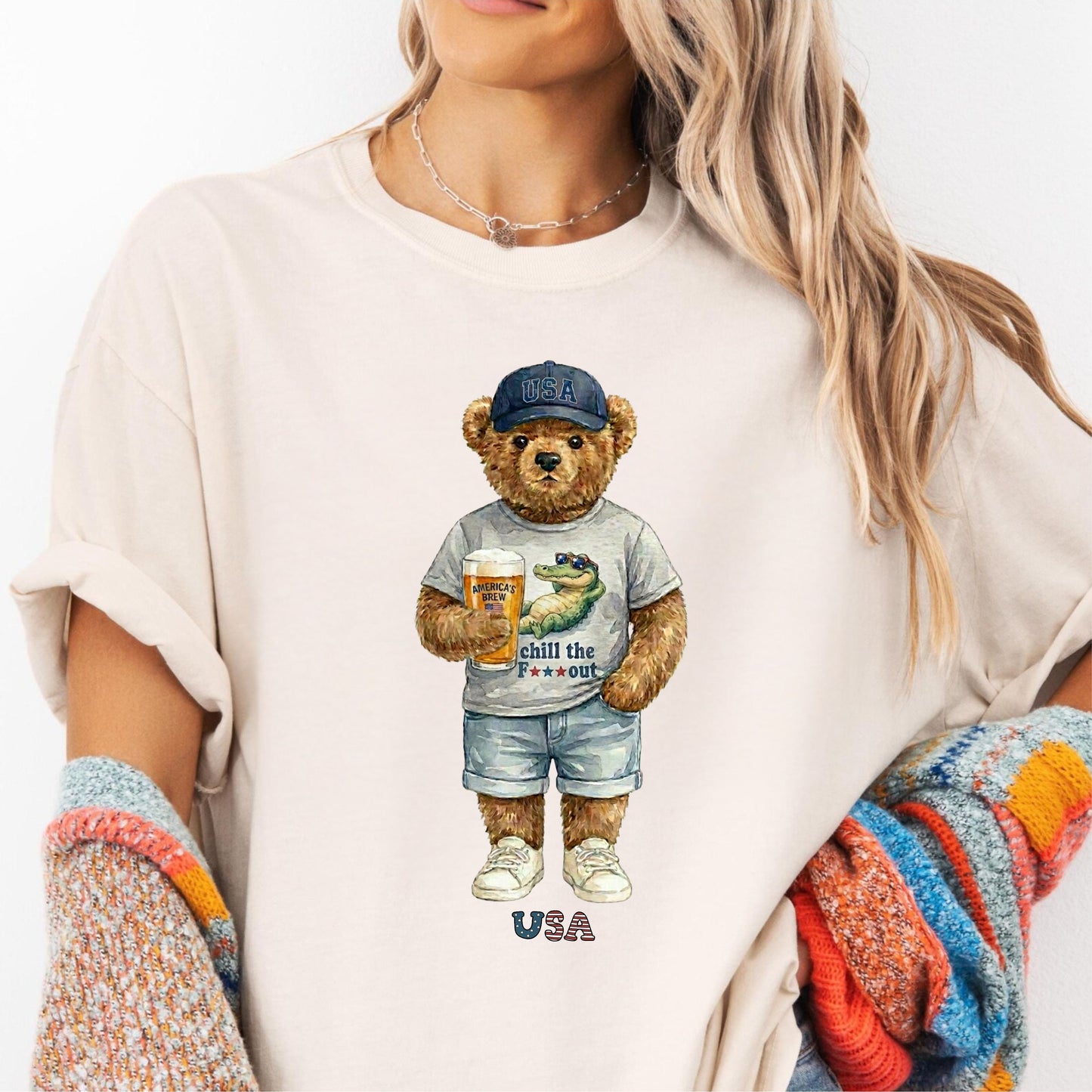 Person wearing an ivory t-shirt with a bear graphic holding a beer mug and a bottle, with 'USA' text.