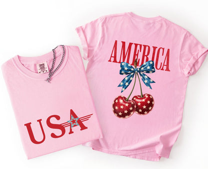Two pink t-shirts with 'USA' and 'AMERICA' designs on a white background