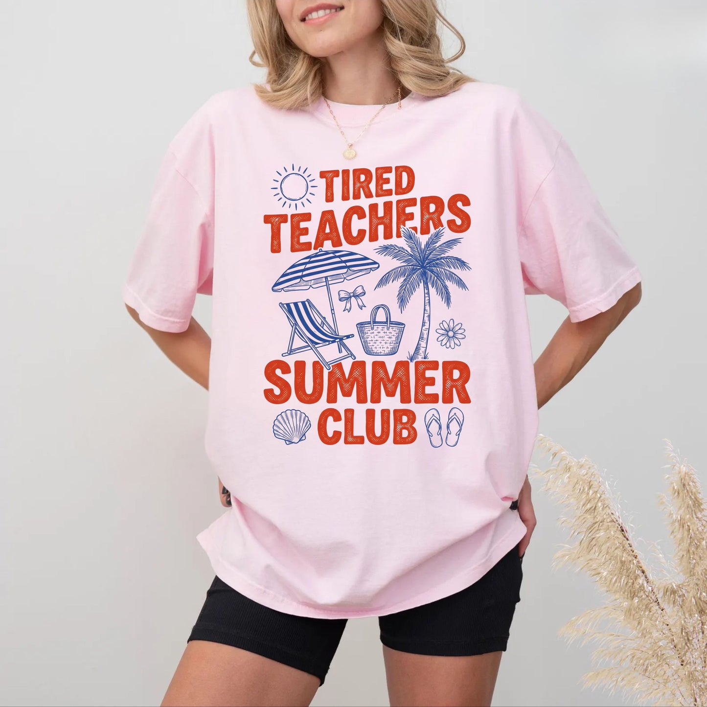 Person wearing a pink t-shirt with 'Tired Teachers Summer Club' design on a plain background