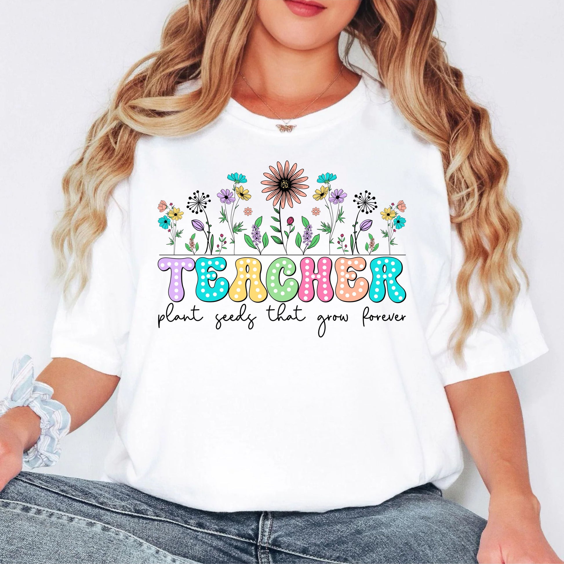 White t-shirt with colorful floral design and 'Teacher' text worn by a person.