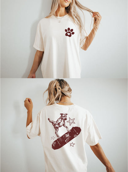 ivoryt-shirt with a red paw print design worn by a person, shown from front and back views. back has a dog skateboarding
