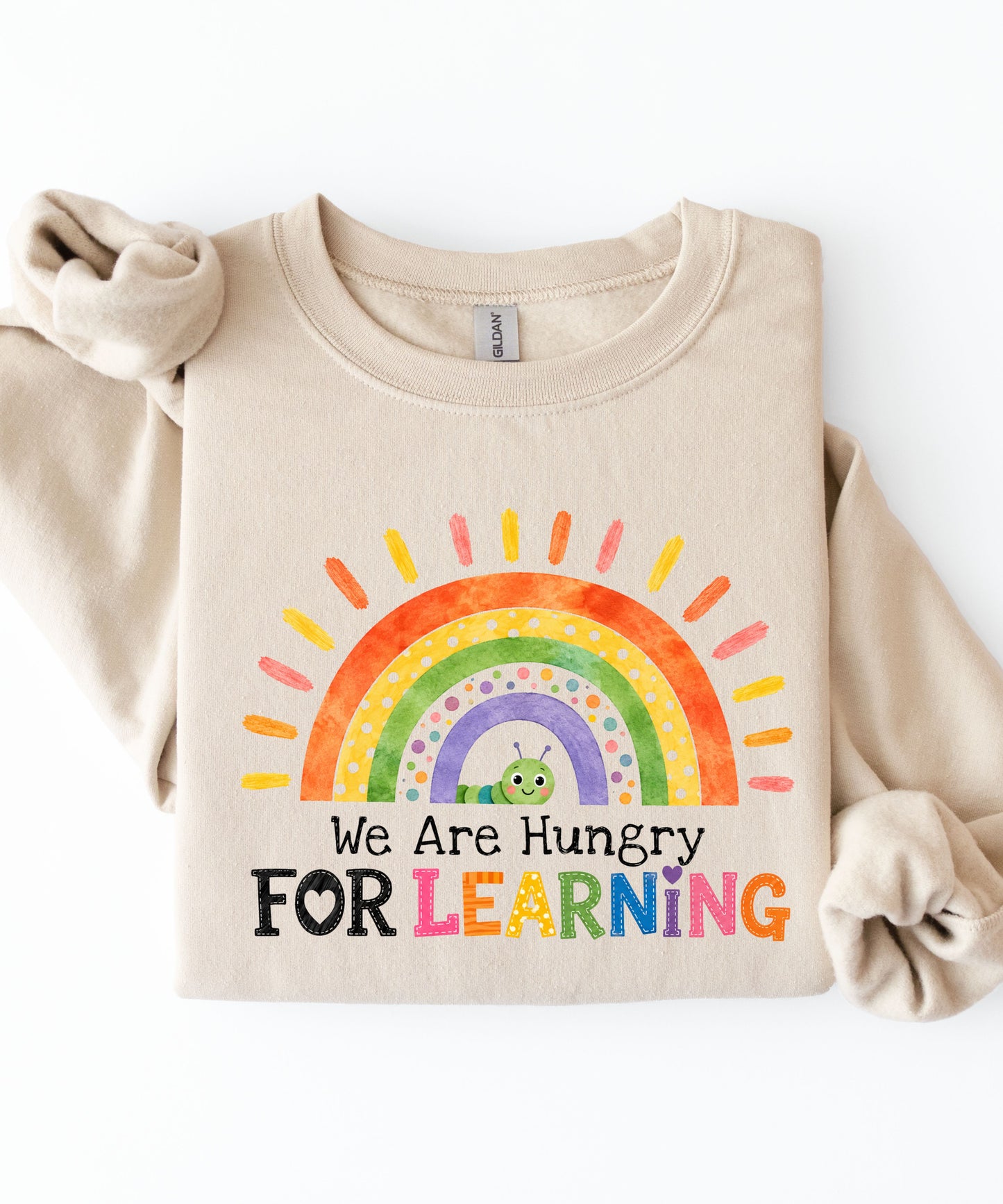 a sand sweatshirt with a rainbow and text that says we are hungry for learning design.
