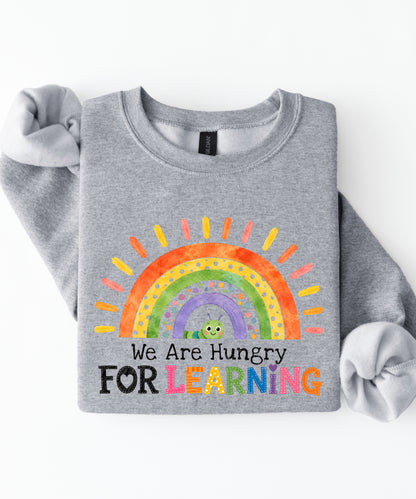 a sports gray sweatshirt with a rainbow and text that says we are hungry for learning design.