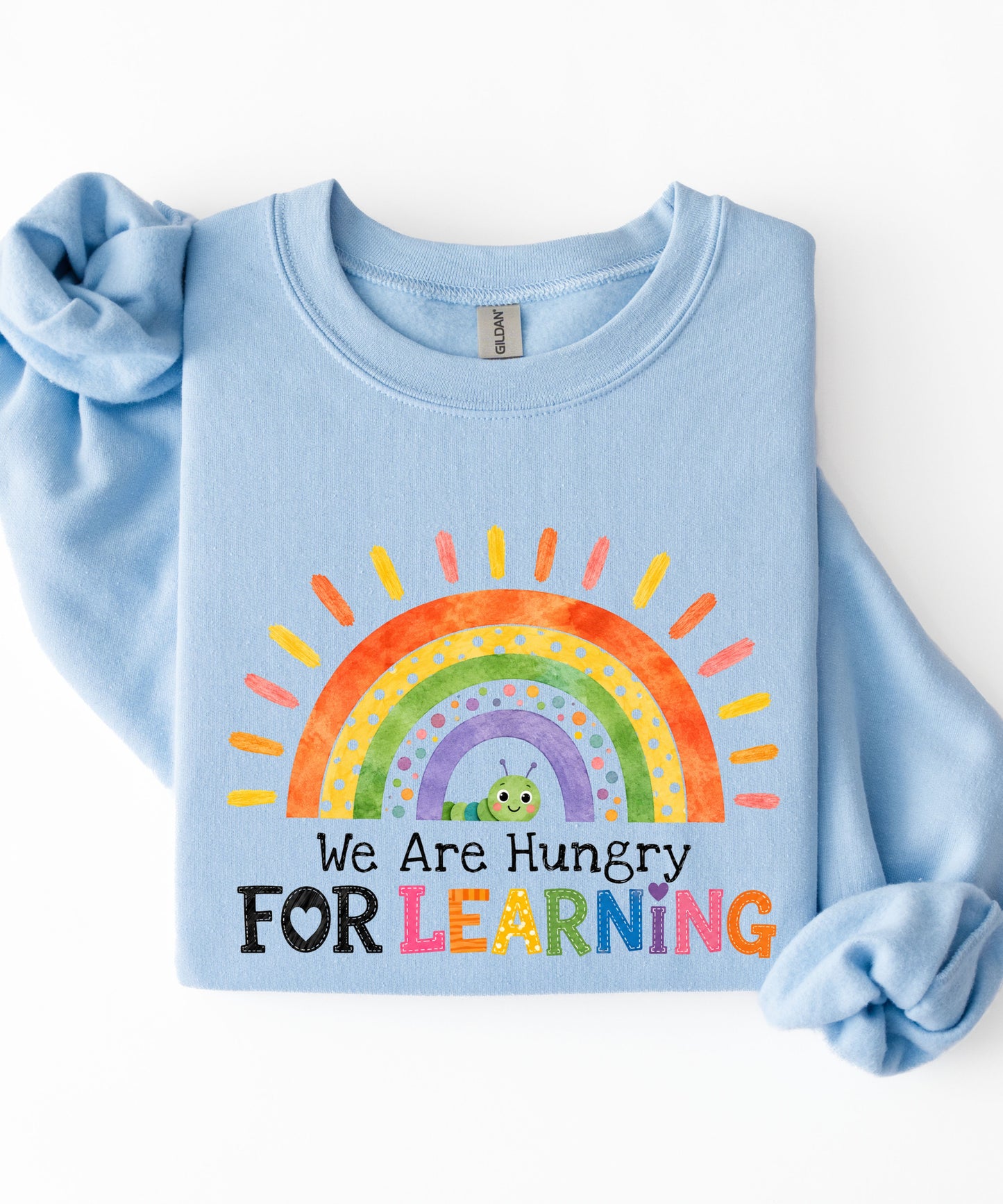 a light blue sweatshirt with a rainbow and text that says we are hungry for learning design.