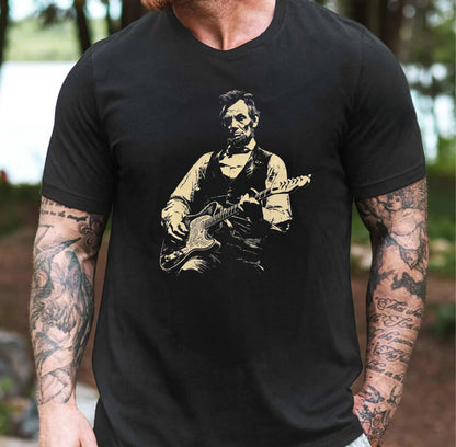 Person wearing a black t-shirt with a graphic of a historical figure playing guitar outdoors.