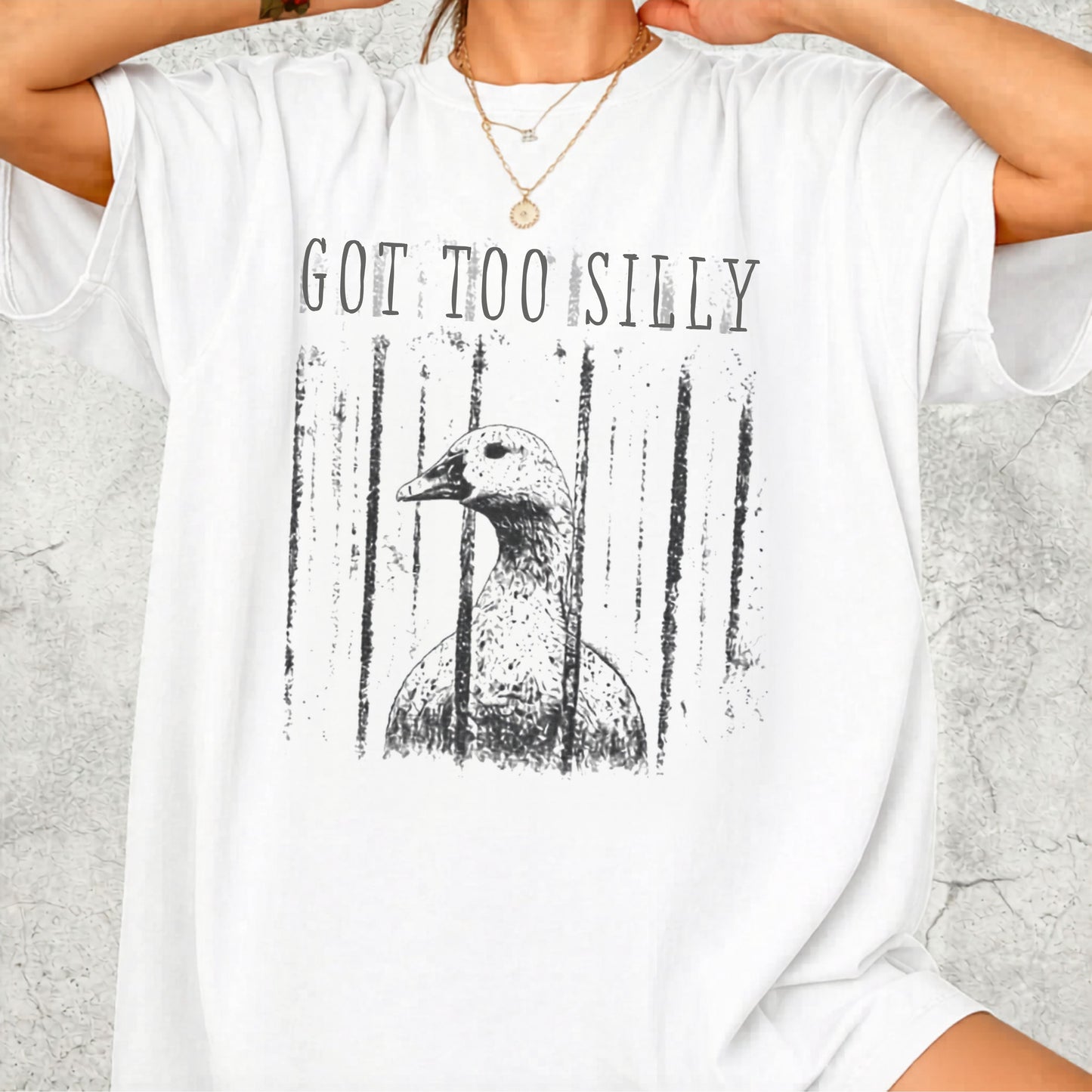 Person wearing a white t-shirt with a graphic of a goose and text 'GOT TOO SILLY' on a light gray background