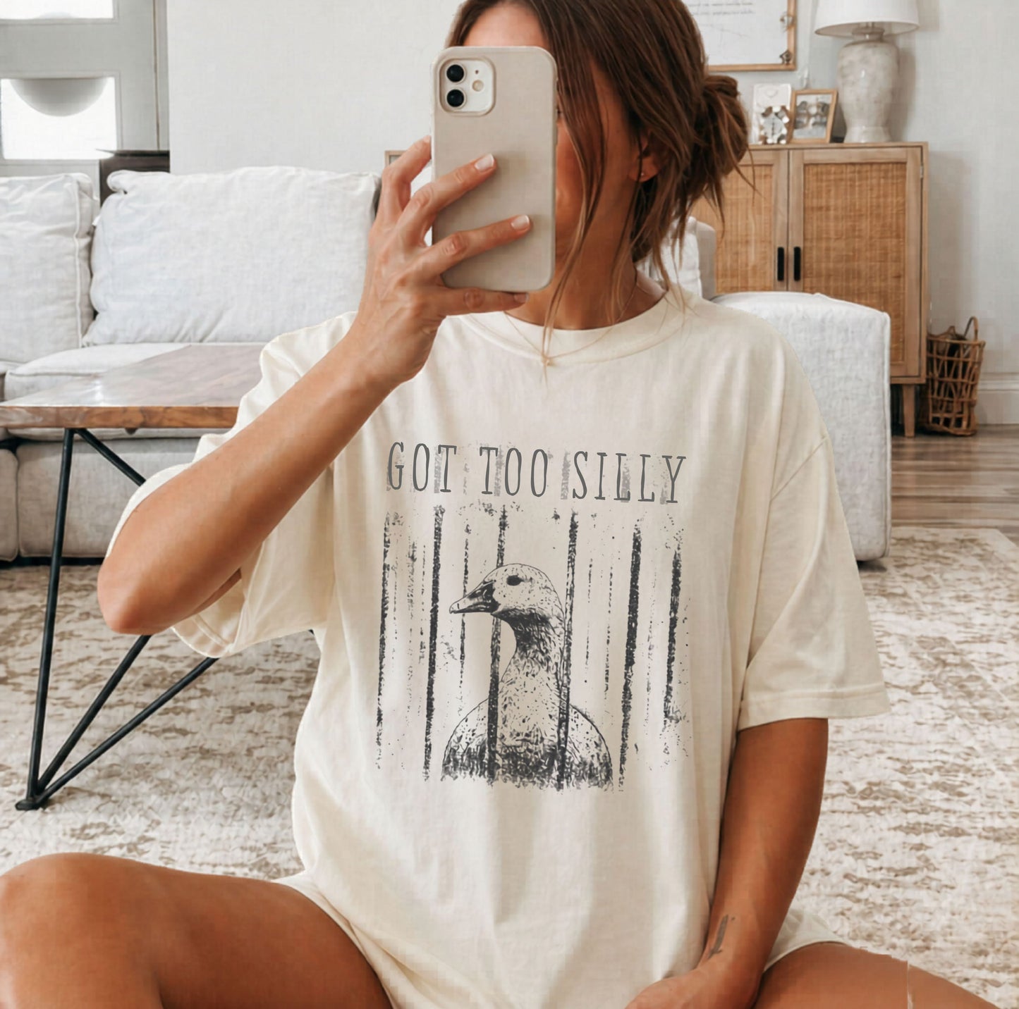Person wearing an ivory t-shirt with a graphic of a goose and text 'GOT TOO SILLY' on a light gray background
