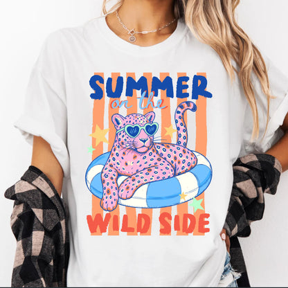 White t-shirt with a colorful graphic of a panther on an inner tube and text 'Summer on the Wild Side' worn by a person.