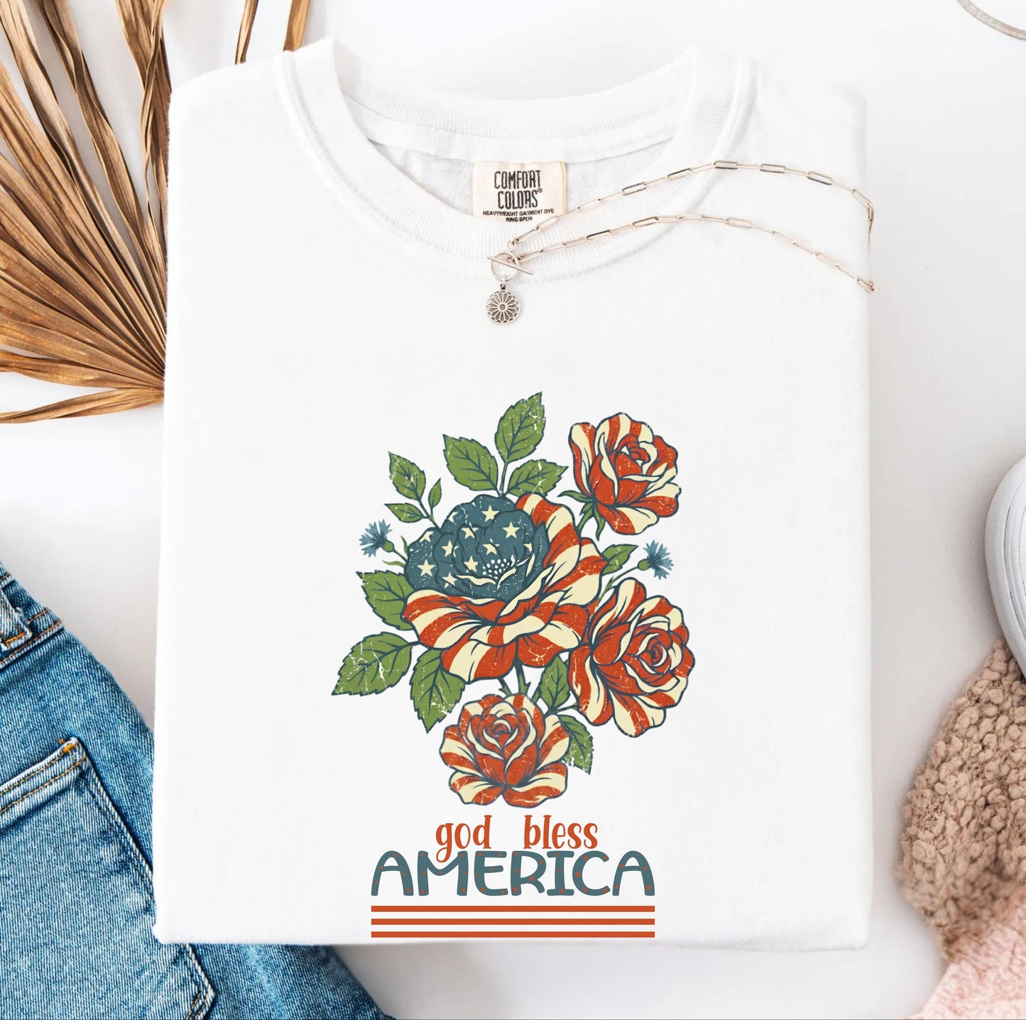 White garment-dyed t-shirt with patriotic floral God Bless America graphic on chest
