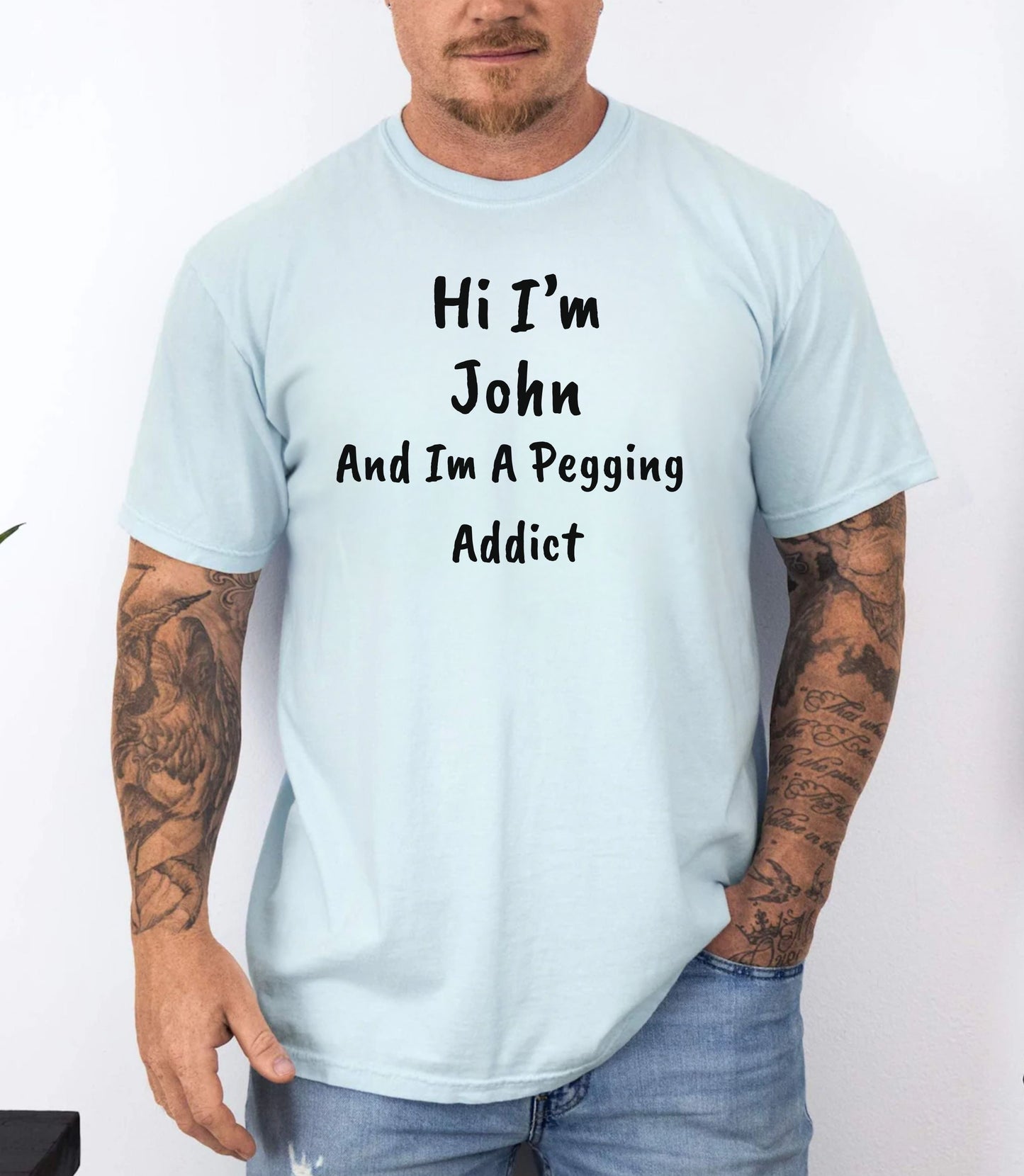 Chambray garment-dyed heavyweight t-shirt with personalized 'Hi I'm [Name] And I'm A Pegging Addict' graphic in handwritten-style font, centered on chest