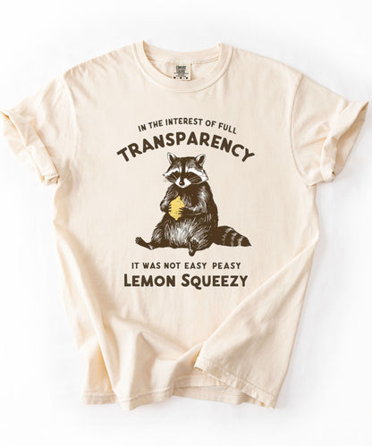 Funny raccoon sarcastic meme t-shirt in Ivory — "Was Not Easy Peasy Lemon Squeezy" graphic tee